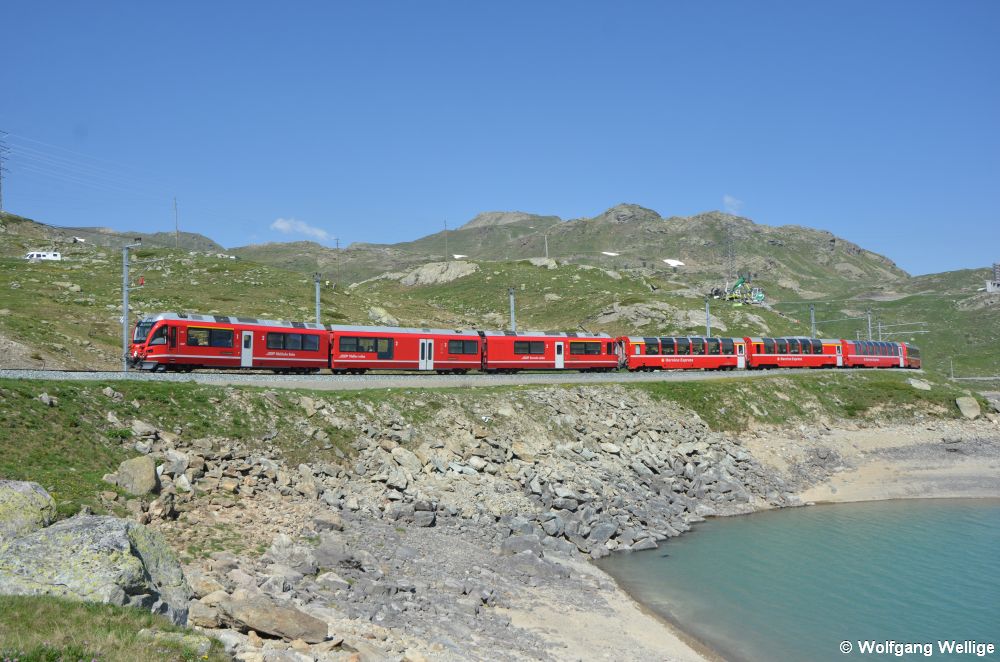 Auf der Passhöhe der Berninastrecke, die oberhalb der Baumgrenze liegt, fährt Allegra-Triebwagen 3507 mit einigen Panoramawagen im Schlepptau am Ufer des Lago Bianco entlang. (29.06.2019)