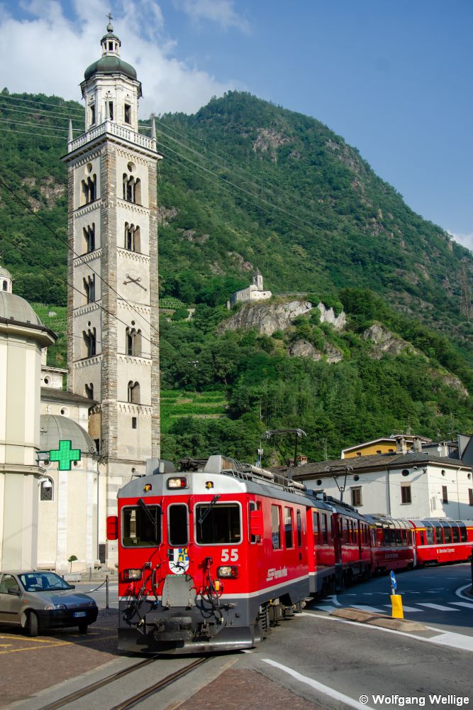 Mitten über den Platz vor der Basilika in Tirano verläuft die Trasse des Bernina-Express wenige hundert Meter vor seinem Endbahnhof. Am 30.06.2019 rollt Schlepptriebwagen 55 der Bauart ABe 4/4 III mit Zug R 4605 von Poschiavo nach Tirano.